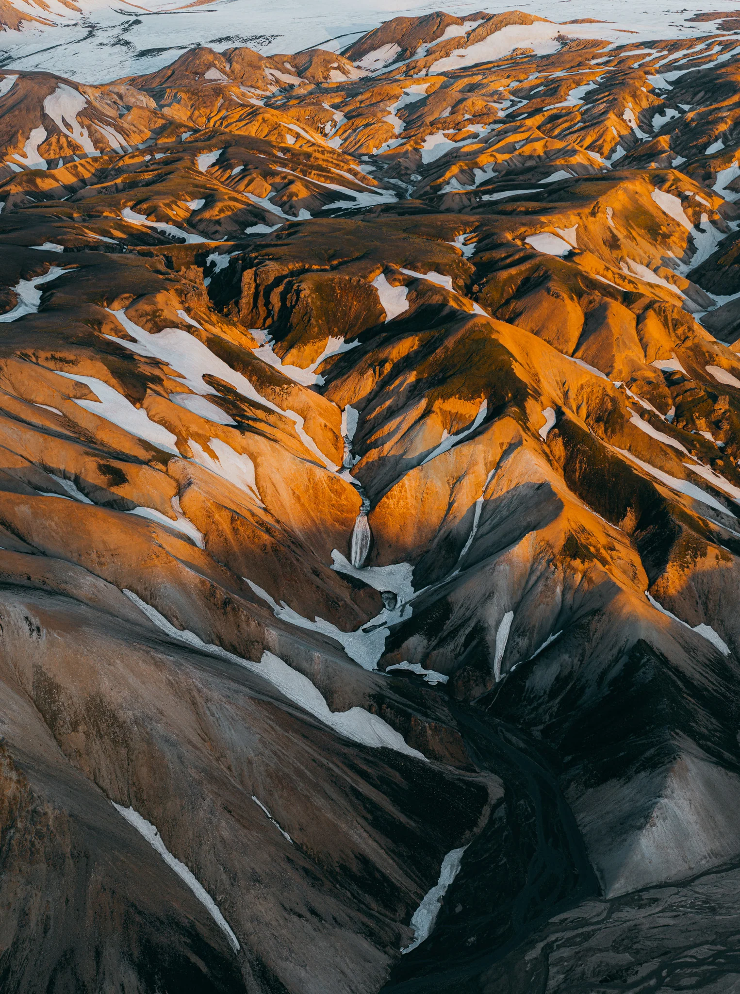 Snow traced across orange mountains in the Icelandic Highlands